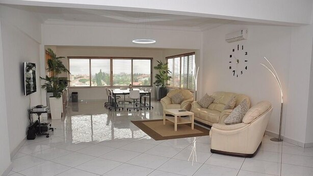 A spacious living room with a sofa, coffee table, and dining area with chairs. - Le Suites Serviced Apartments (Accra)