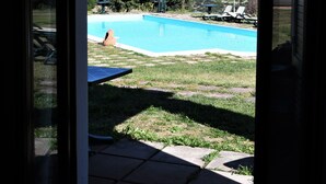Vista a través de un ventanal hacia una piscina con montañas al fondo.