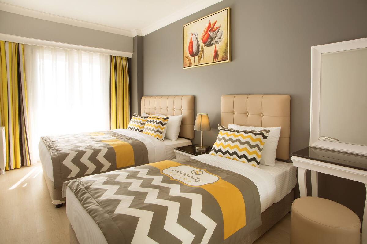 A hotel room with two beds, a TV, and a painting on the wall.