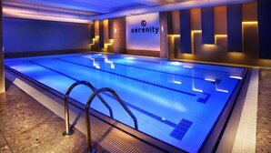 Una piscina con el logotipo 'serenity', paredes con azulejos y un diseño moderno.