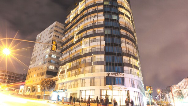 Un hotel moderno con fachada curva, varios balcones y un letrero llamativo que dice 'serenity suites'.