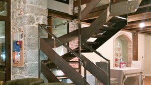 A spiral staircase with metal railings in a room with stone walls, a wooden ceiling, and a table with a white tablecloth. - La Corte dei Limoni (Acireale)