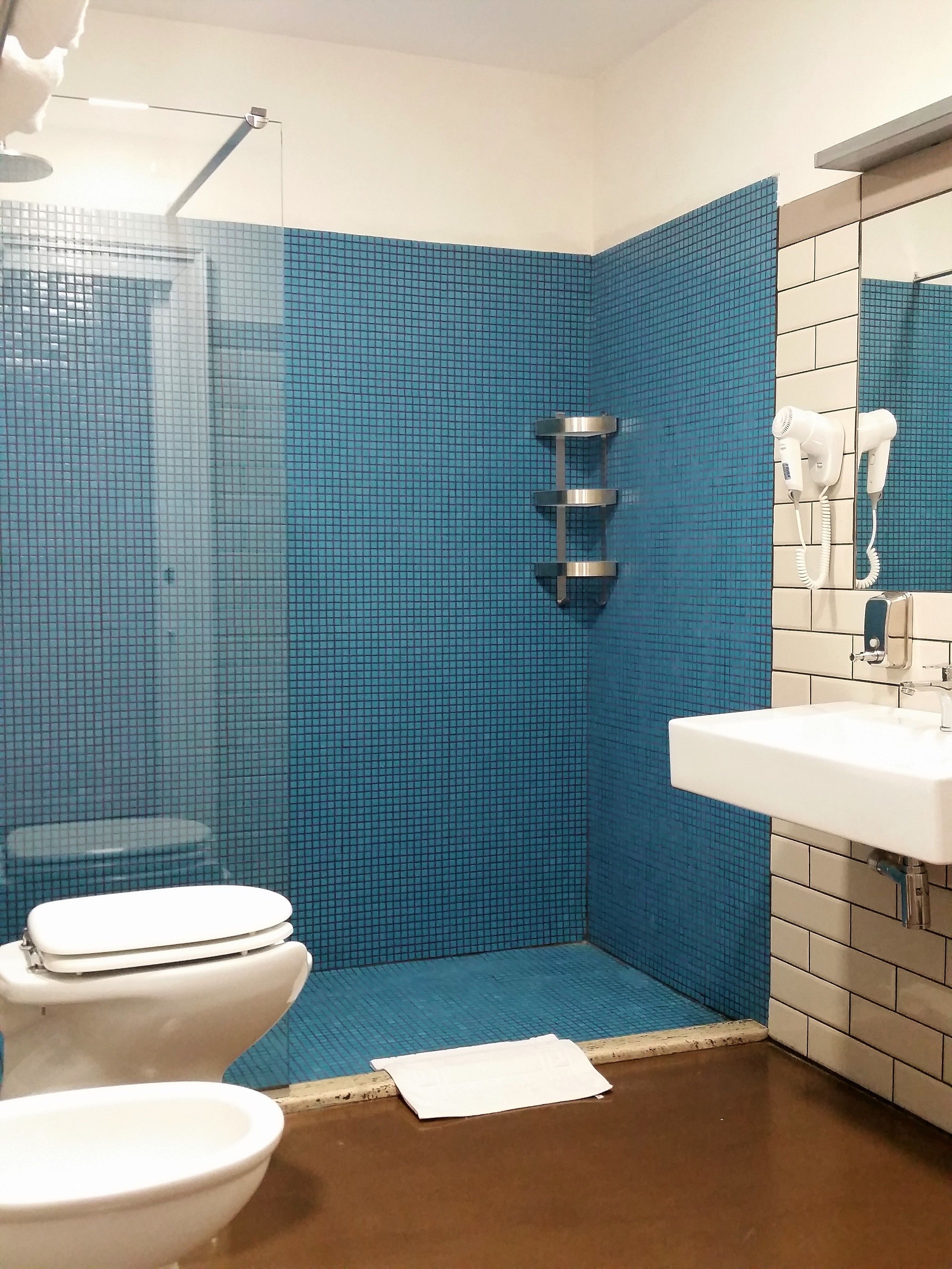 A bathroom with a blue tiled wall, a white sink, and a toilet.