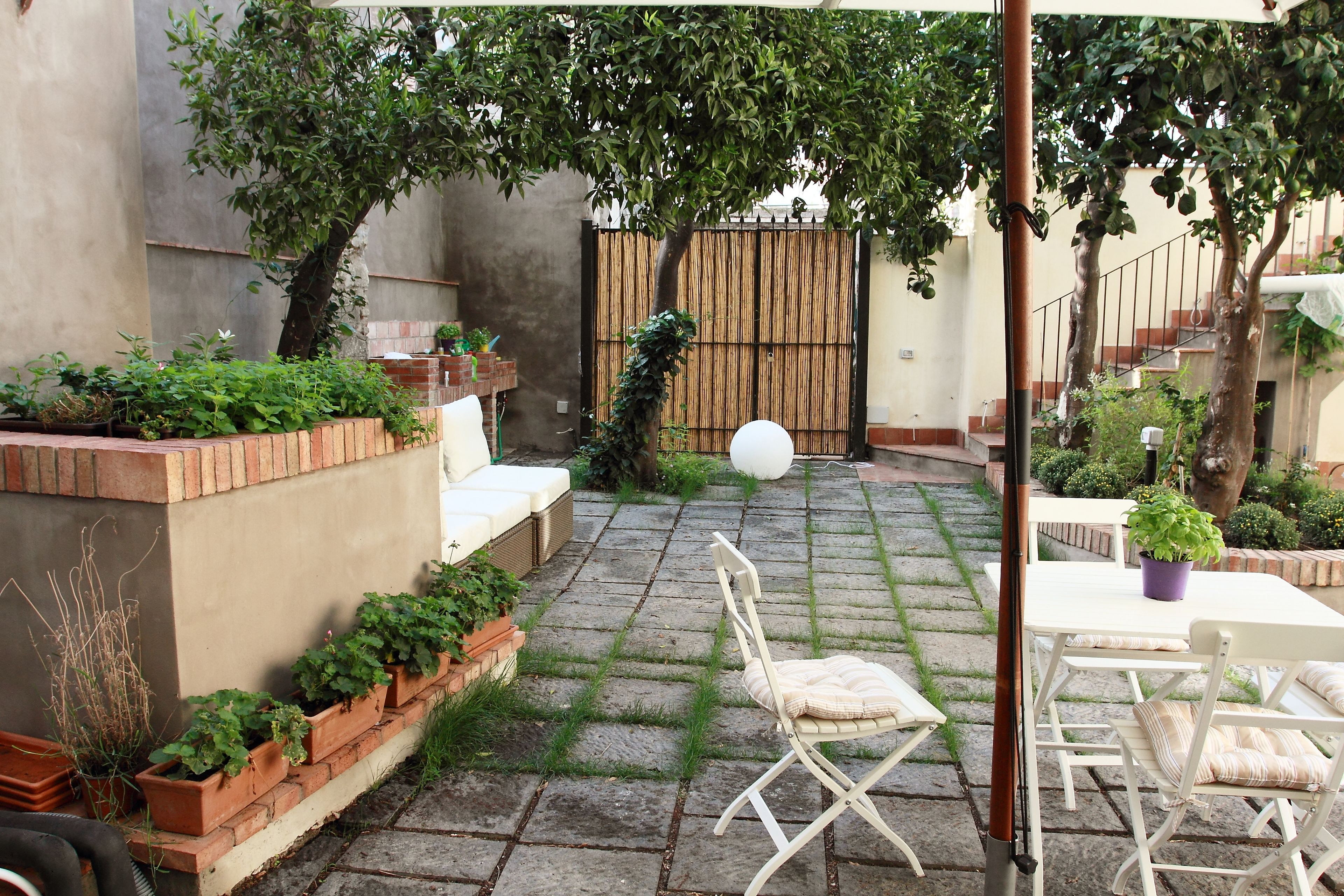 A patio with a white table and chairs, surrounded by potted plants and a bamboo fence.