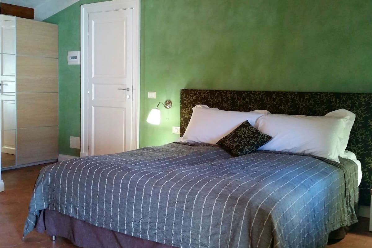 A bedroom with a bed, a nightstand, a lamp, and a wardrobe.