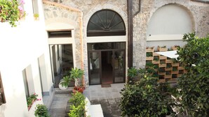 A courtyard with a stone wall, a bench, potted plants, and a wooden planter with flowers. - La Corte dei Limoni (Acireale)