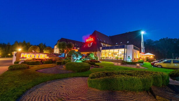 A hotel with a prominent 'HOTEL' sign, well-maintained gardens, and a modern building design. - Hotel Na Półboru (Sieradz)