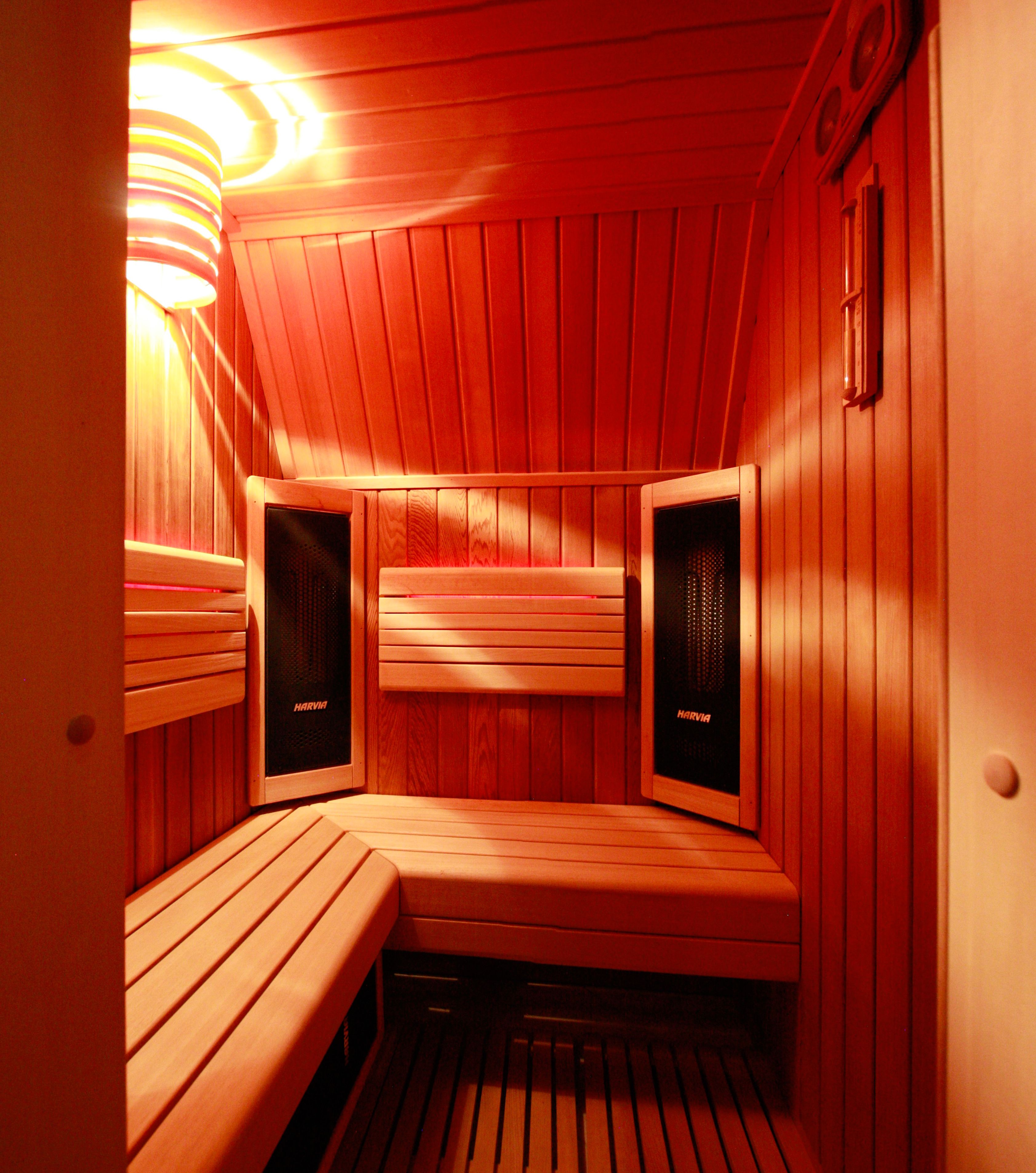A sauna with wooden benches and walls, and two speakers labeled "HARVIA".