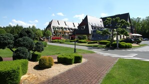 A hotel with a modern architectural design, featuring a prominent 'HOTEL' sign, landscaped gardens, and a paved walkway. - Hotel Na Półboru (Sieradz)