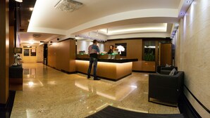A hotel lobby with a reception desk, a seating area, and a large mirror. - Hotel Na Półboru (Sieradz)