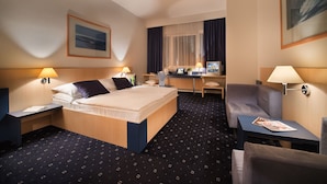 Habitación de hotel con cama, escritorio, silla y vista a la ciudad por la ventana.