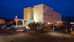 Un hotel con diseño moderno, entrada cubierta y zona de estacionamiento.