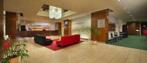 A spacious lobby with a red sofa, a reception desk, and a green carpeted area.