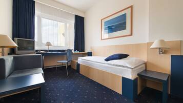 A hotel room with a bed, desk, chair, and a television.