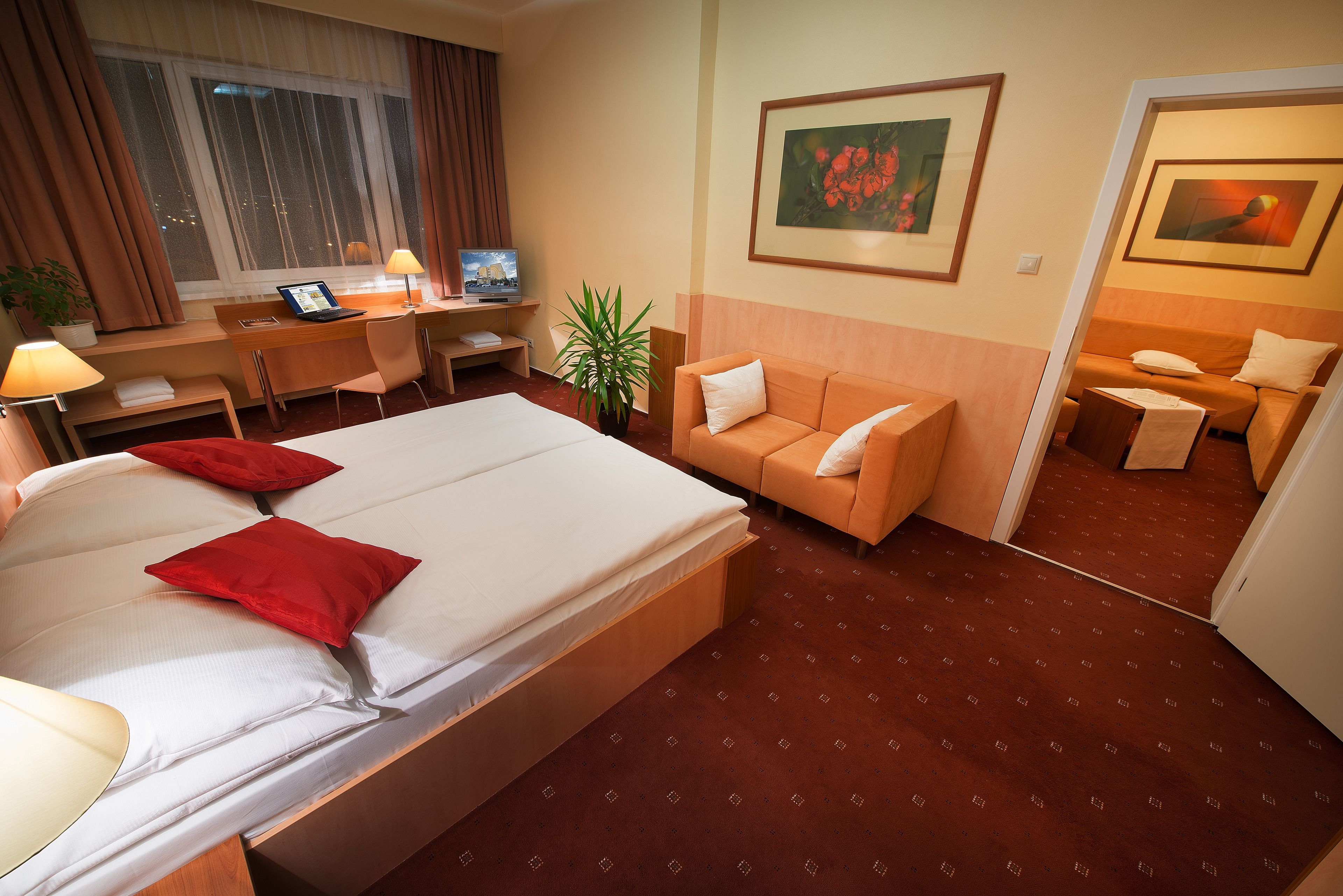 Una habitación de hotel con una cama, un escritorio con una computadora, un sofá y una mesita.