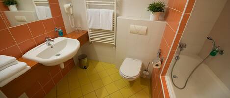A bathroom with a yellow-tiled floor, a white sink, a toilet, and a shower.