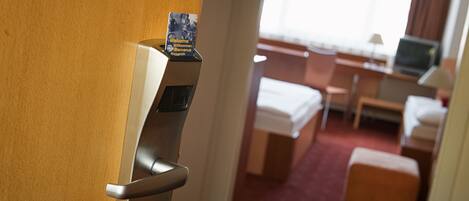 A hotel room with a bed, a desk, a chair, and a small table.
