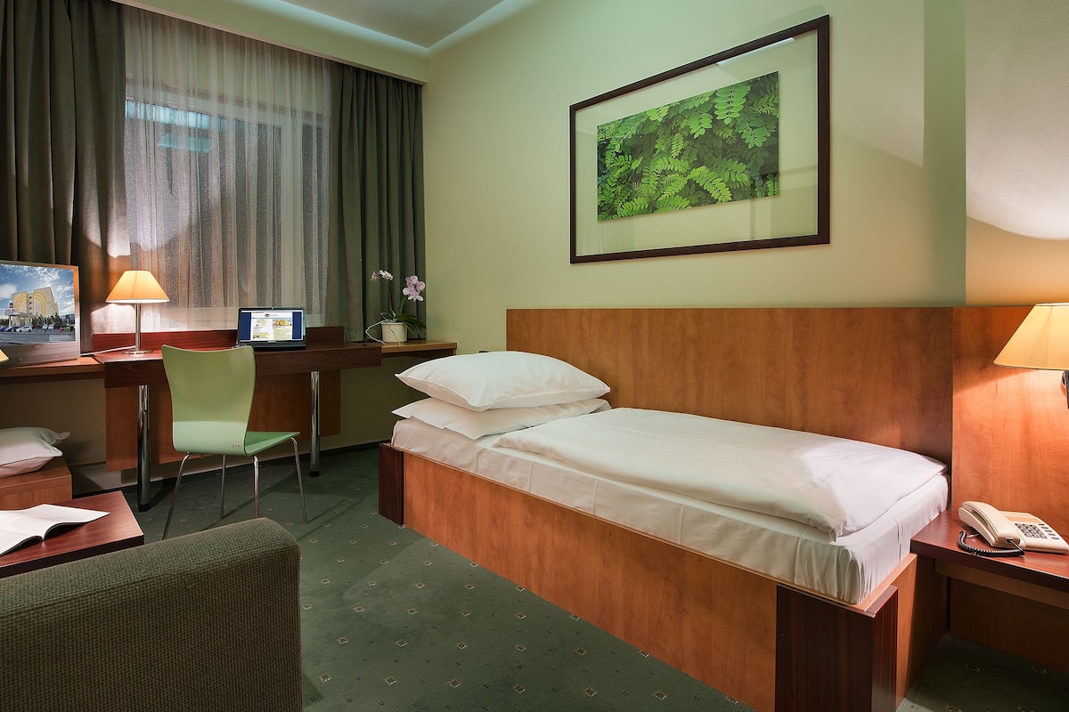 Een hotelkamer met een bed, bureau, stoel en lampen.