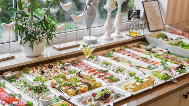 A buffet with various food items and a potted plant. - Villa Atlantis (Kolobrzeg)