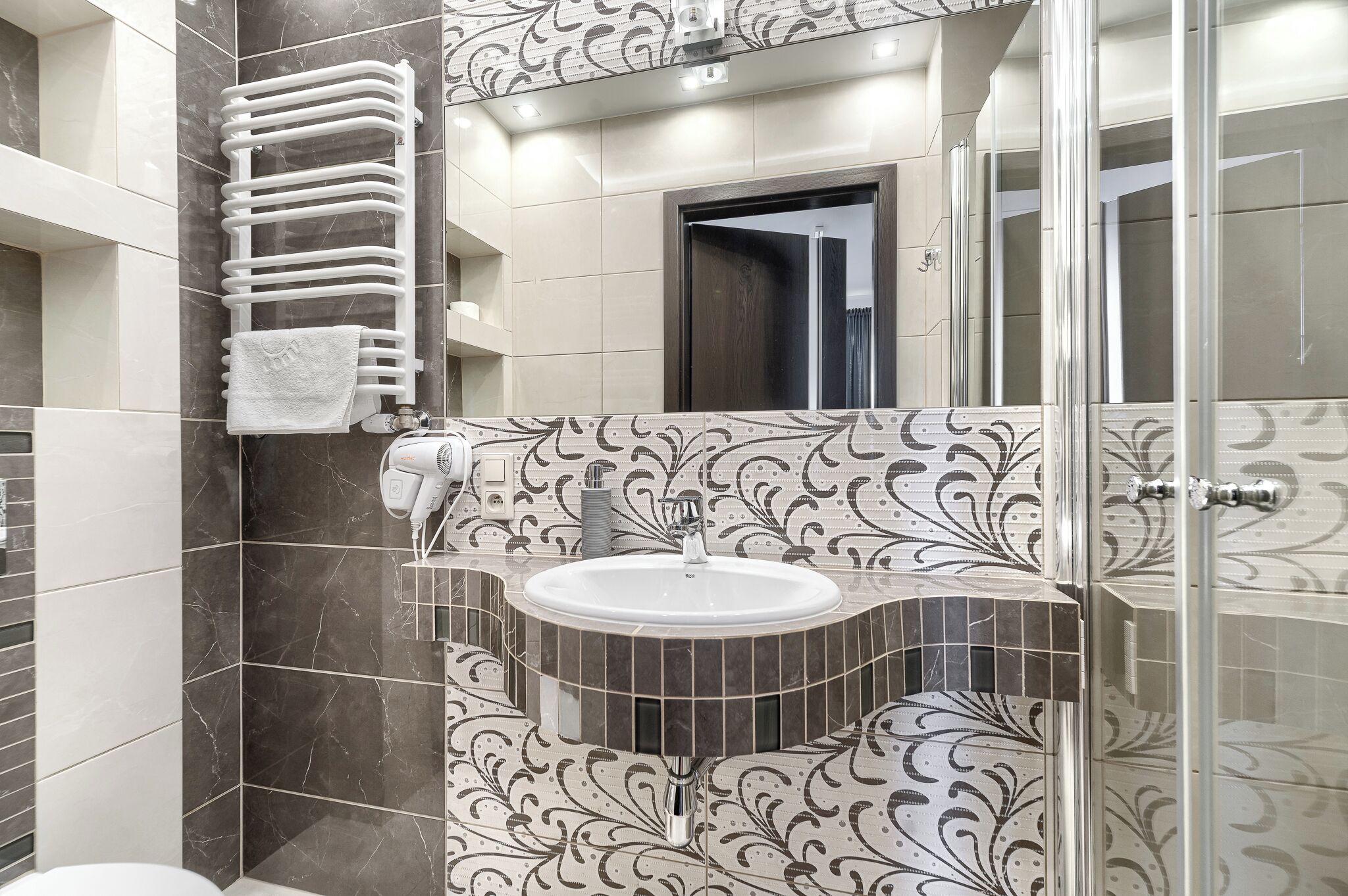 Un baño con tocador, perchero, lavamanos y zona de ducha.