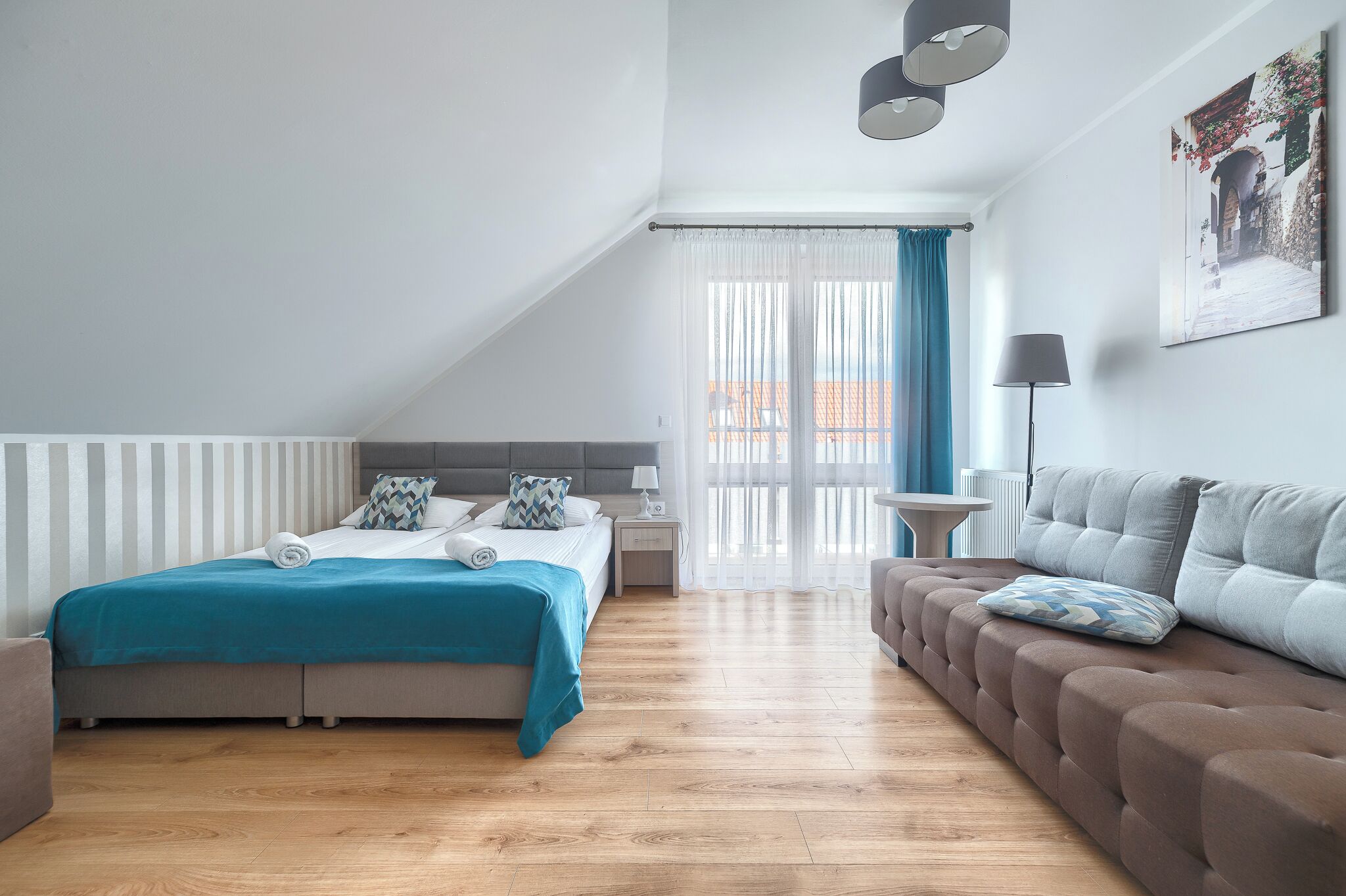 Ein modernes Schlafzimmer mit einem Bett, einem Schlafsofa, einem Nachttisch und einem Fenster mit Vorhängen.