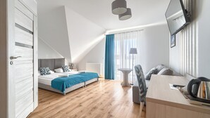 A bedroom with a bed, a desk, a chair, a radiator, and a window with curtains. - Villa Atlantis (Kolobrzeg)