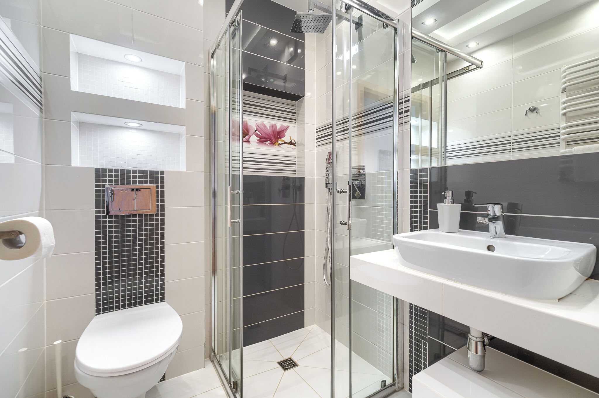 A modern bathroom with a glass-enclosed shower, a white sink, and a toilet.