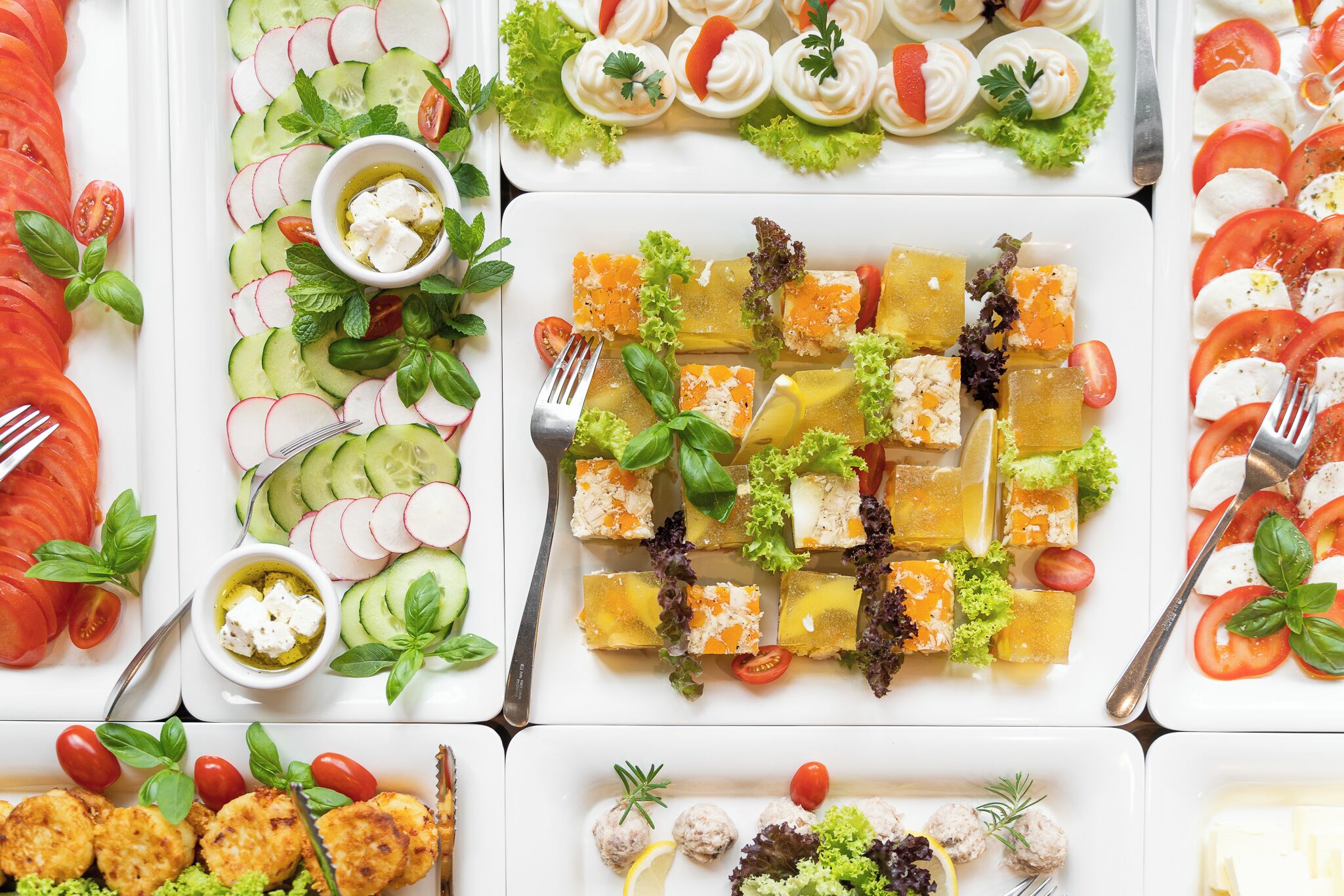 Verschillende gerechten, waaronder een komkommersalade, zalm en gehaktballetjes, gepresenteerd op een grote tafel.