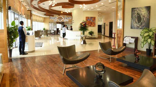 A hotel lobby with a reception desk, seating area, and a large floral arrangement. - Gulf Suites Hotel Amwaj (Amwaj Islands)