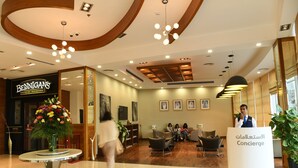 A hotel lobby with a reception desk, seating area, and a large floral arrangement. - Gulf Suites Hotel Amwaj (Amwaj Islands)