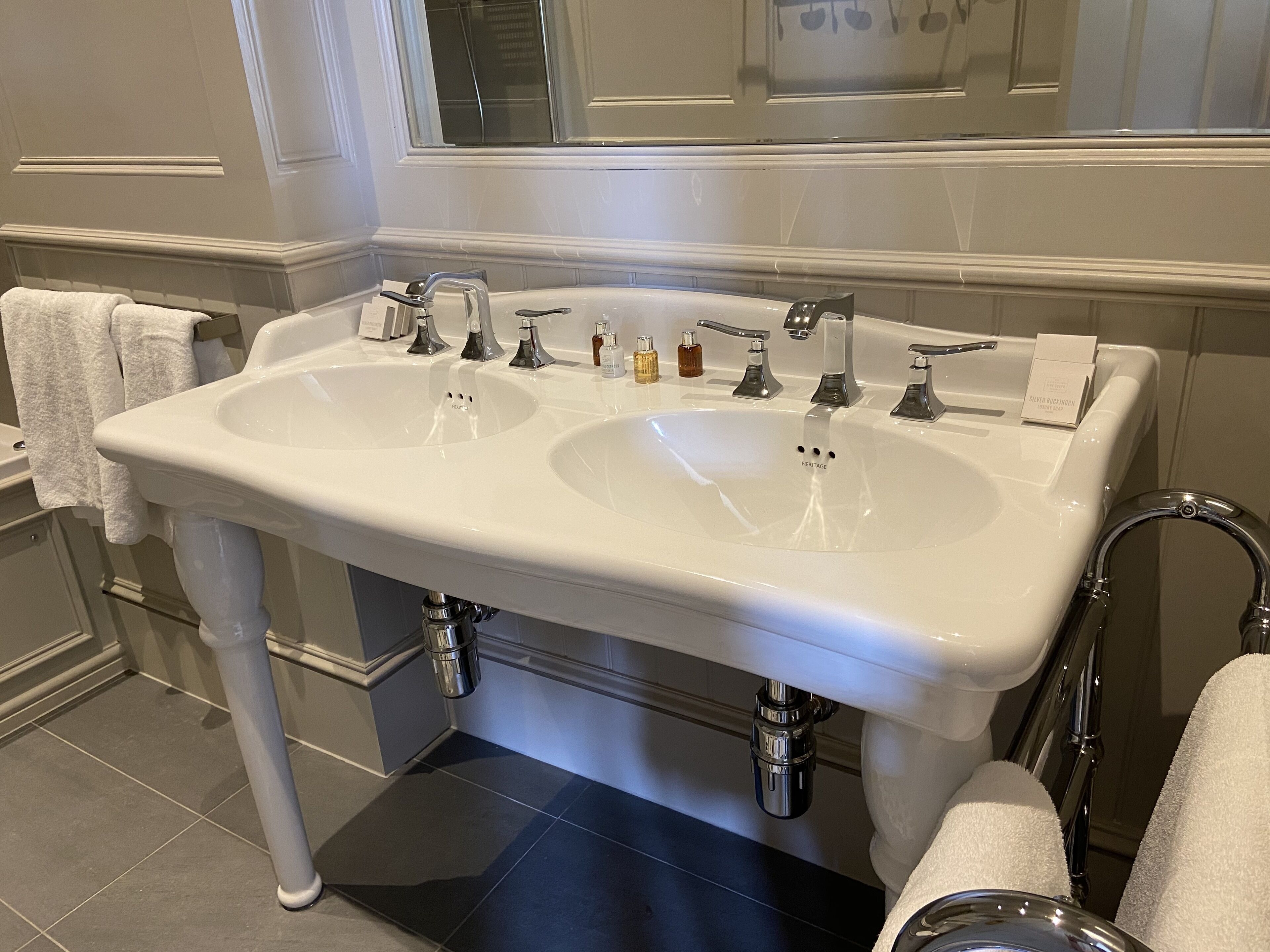 A bathroom with two sinks, a mirror, and a towel rack.