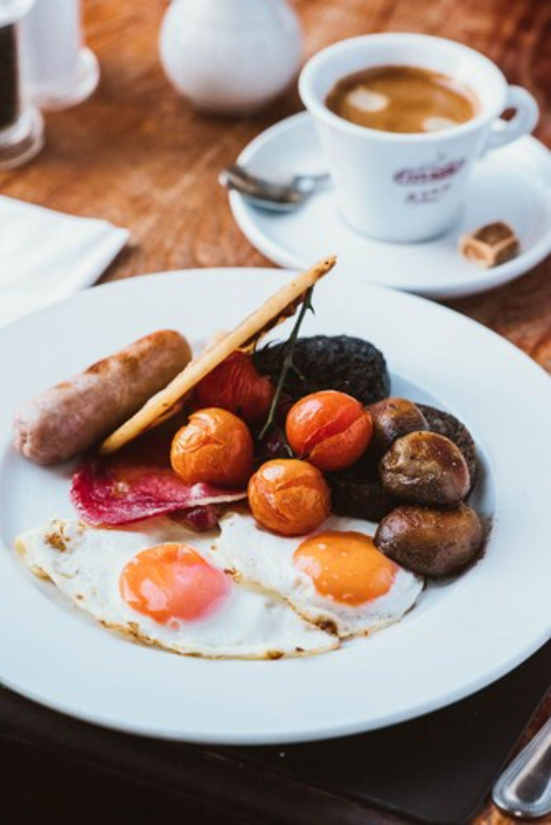A plate of breakfast with sausages, eggs, and tomatoes.