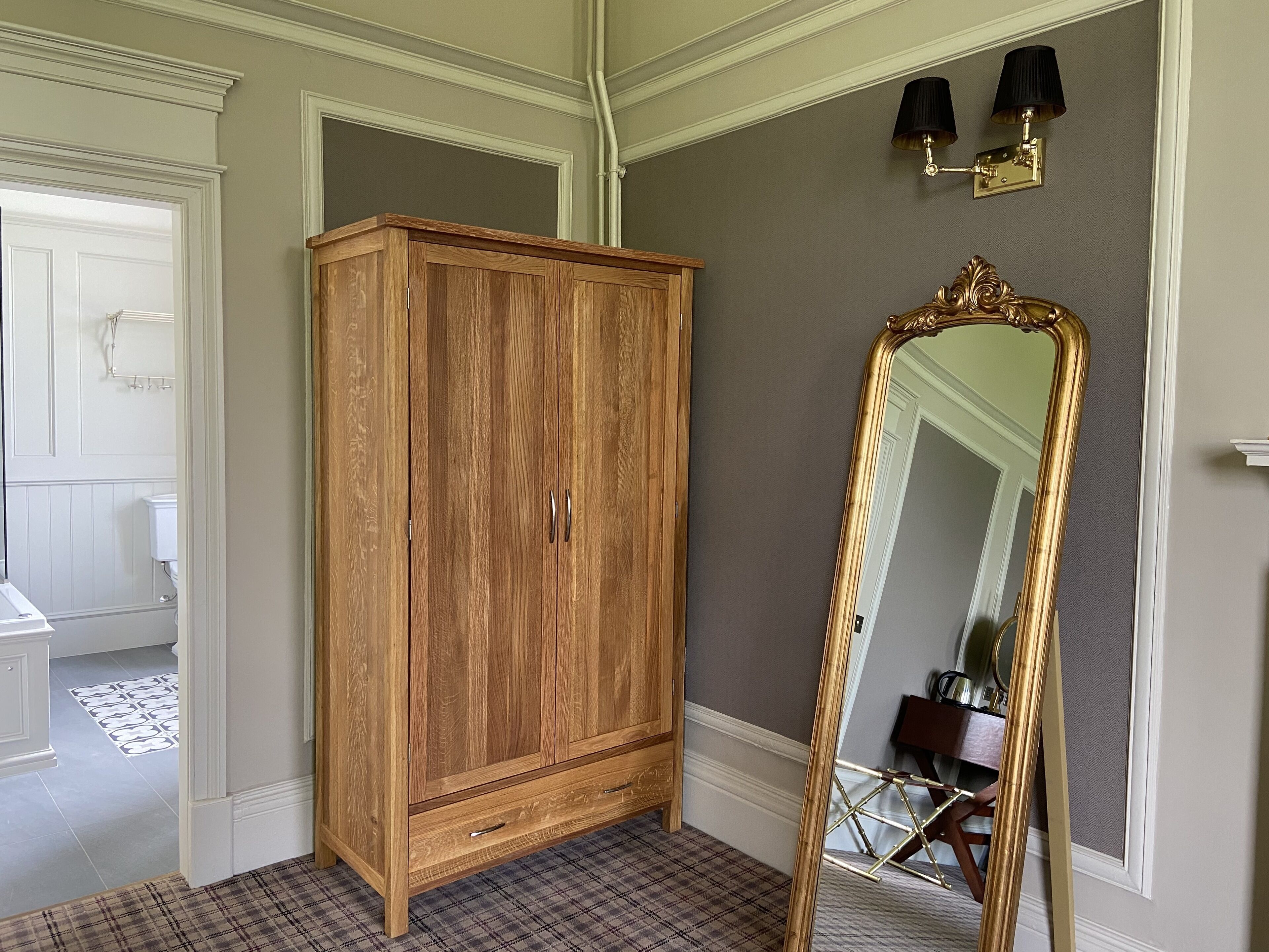 Una habitación con un armario de madera, un espejo grande y un suelo a cuadros.