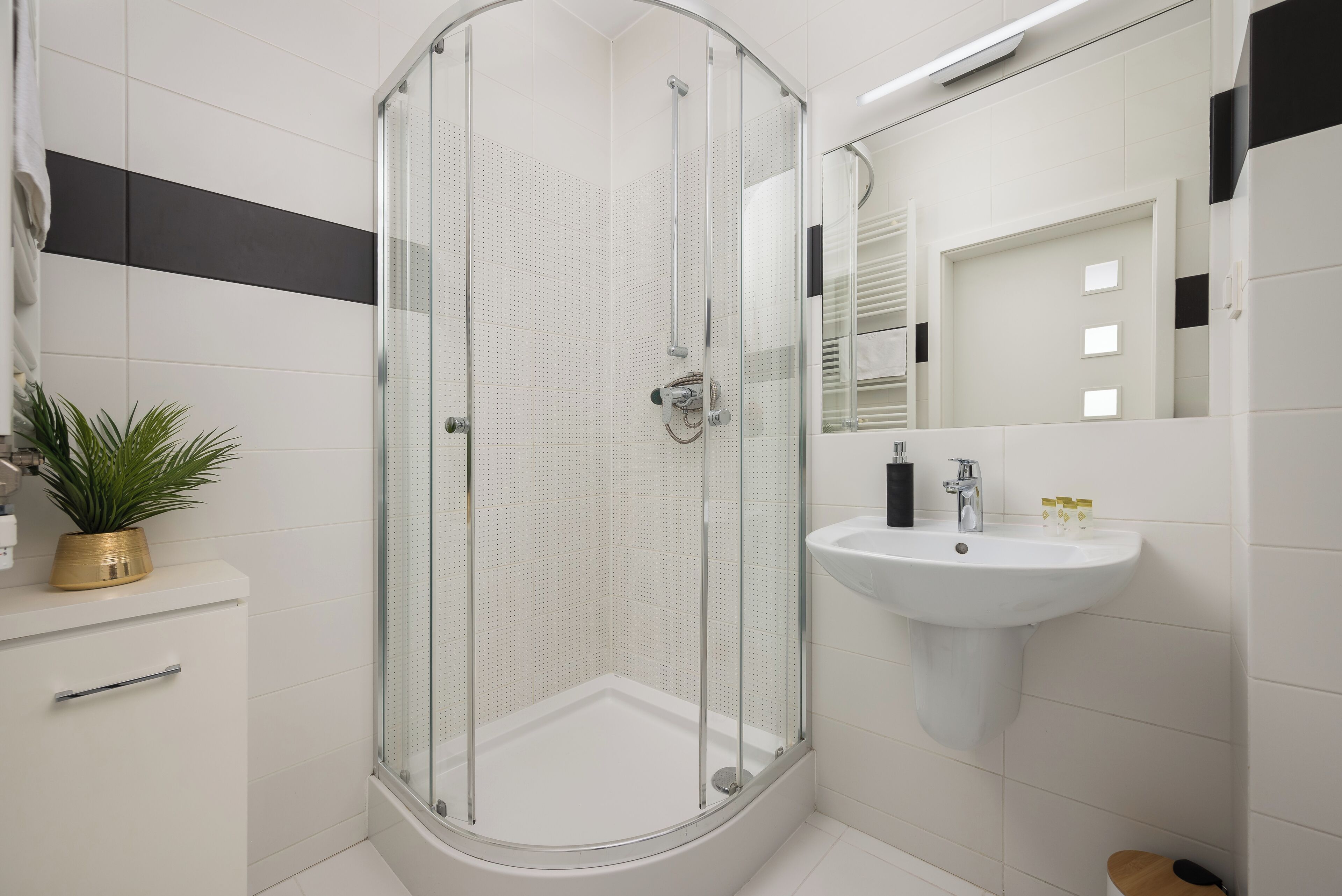 A modern bathroom with a glass-enclosed shower, a white sink, and a mirror above it.