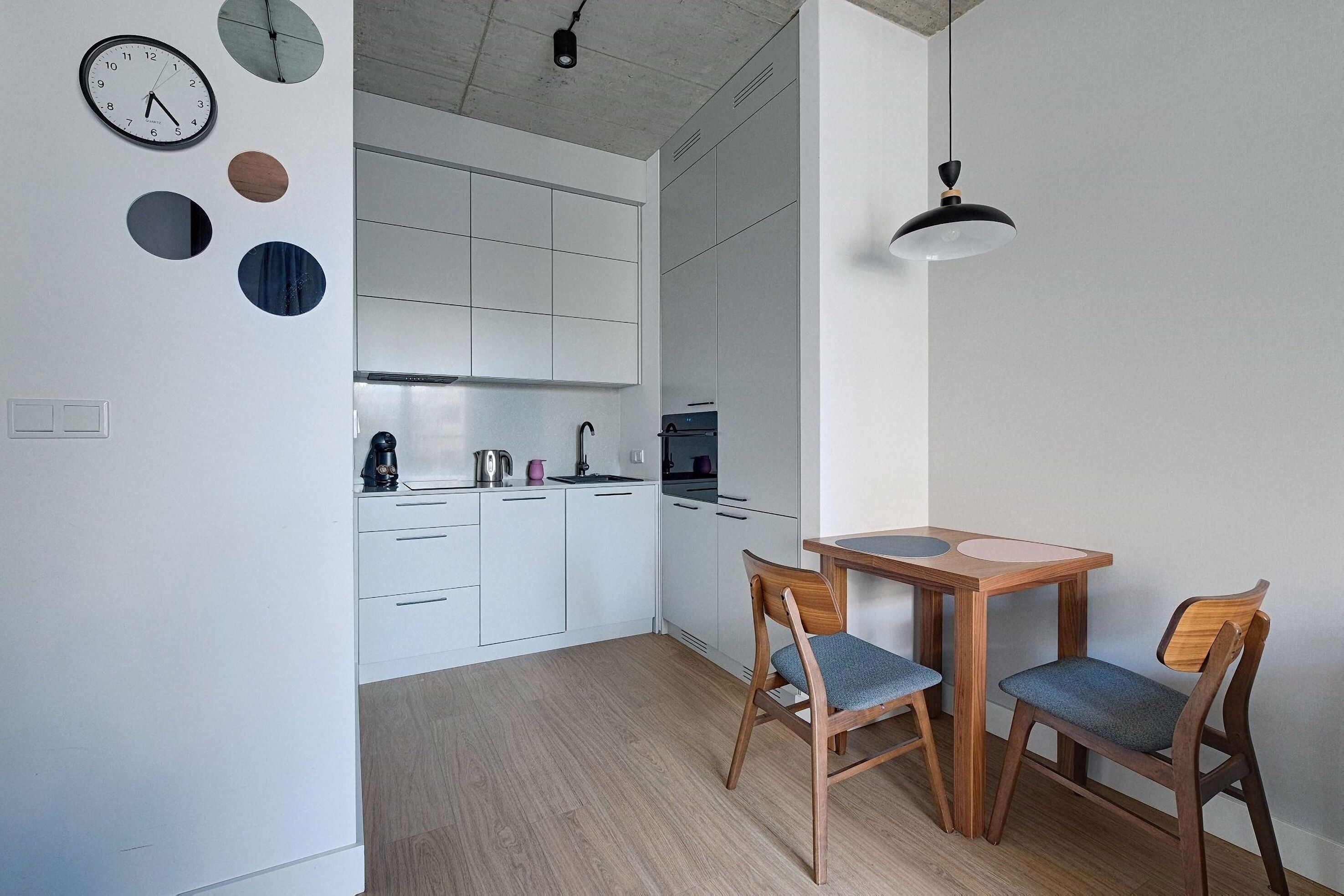 A modern kitchen with white cabinets, a wooden dining table, and two chairs.