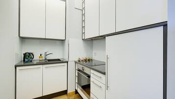 A compact kitchen with white cabinets, a black countertop, and a built-in oven.