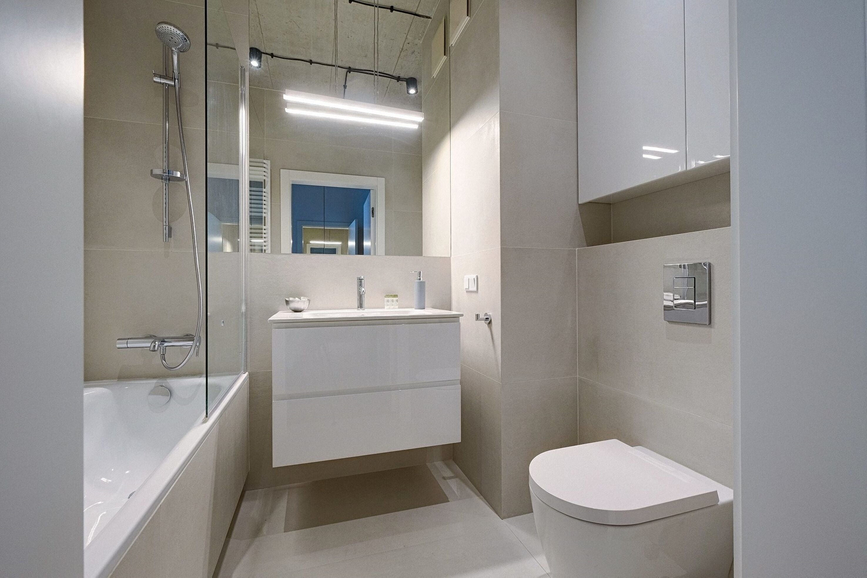 Un baño moderno con bañera, inodoro y tocador con espejo.