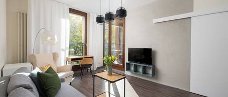 A modern living room with a sofa, a coffee table, a TV, and a dining area.
