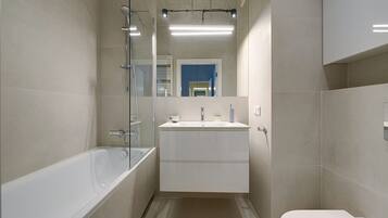 A modern bathroom with a bathtub, sink, and toilet.