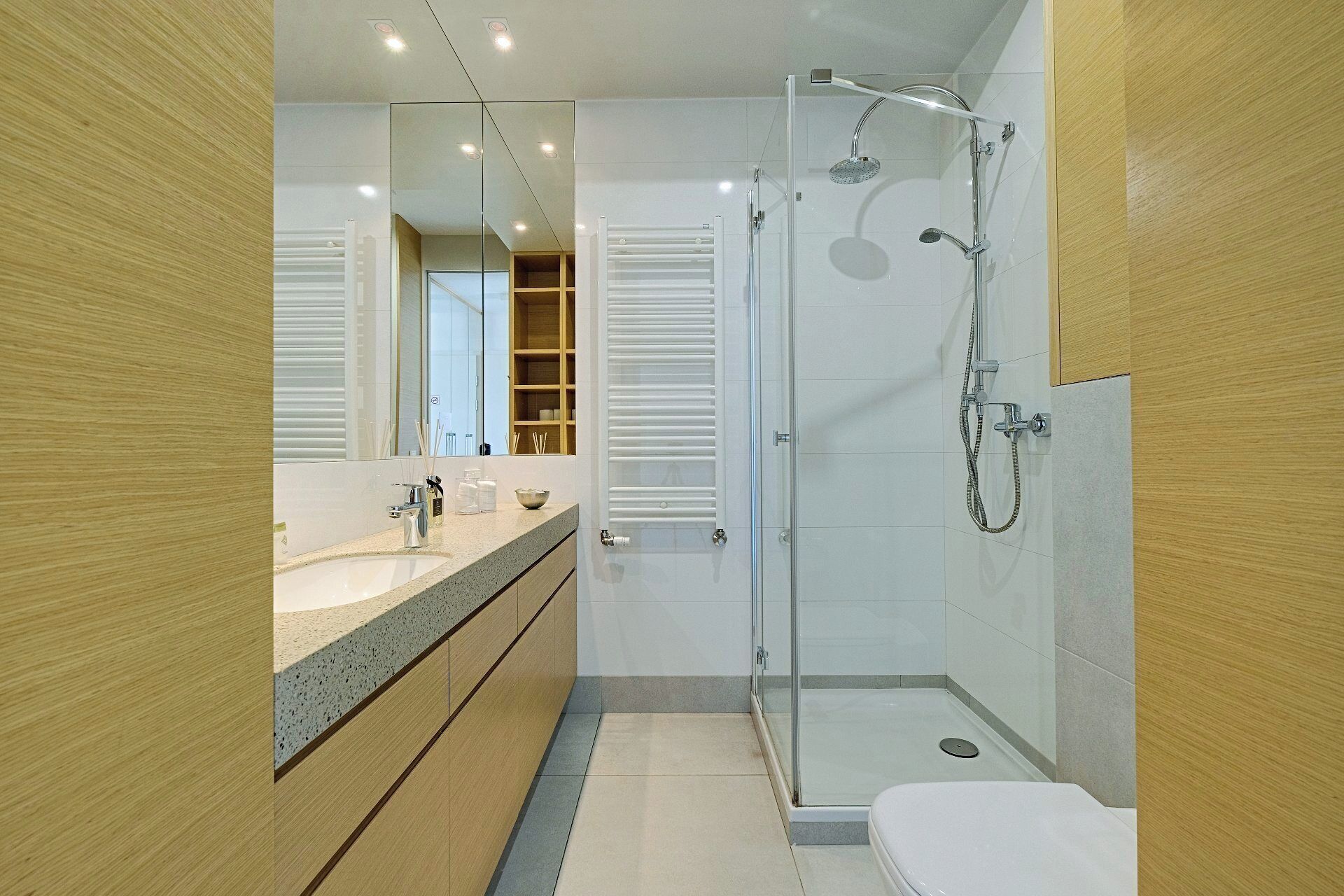 Un baño moderno con ducha envuelta en vidrio, tocador con lavamanos y inodoro.