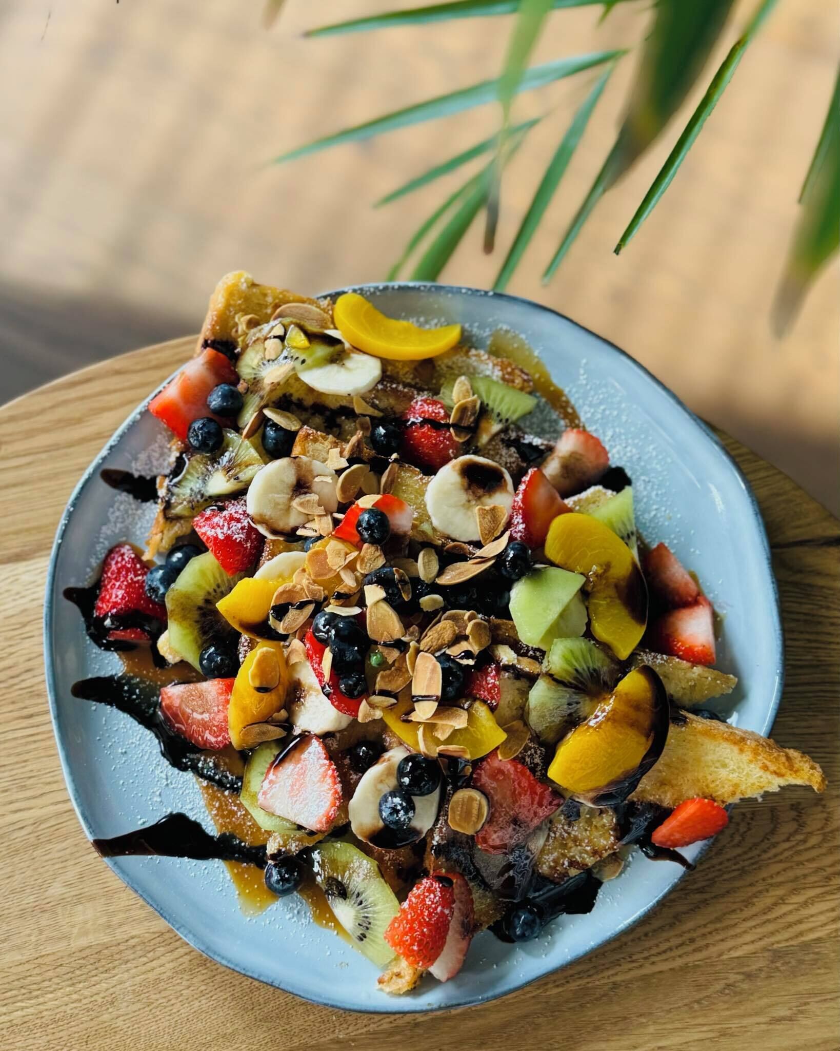 A plate of fruit salad with various fruits and nuts on a blue plate.