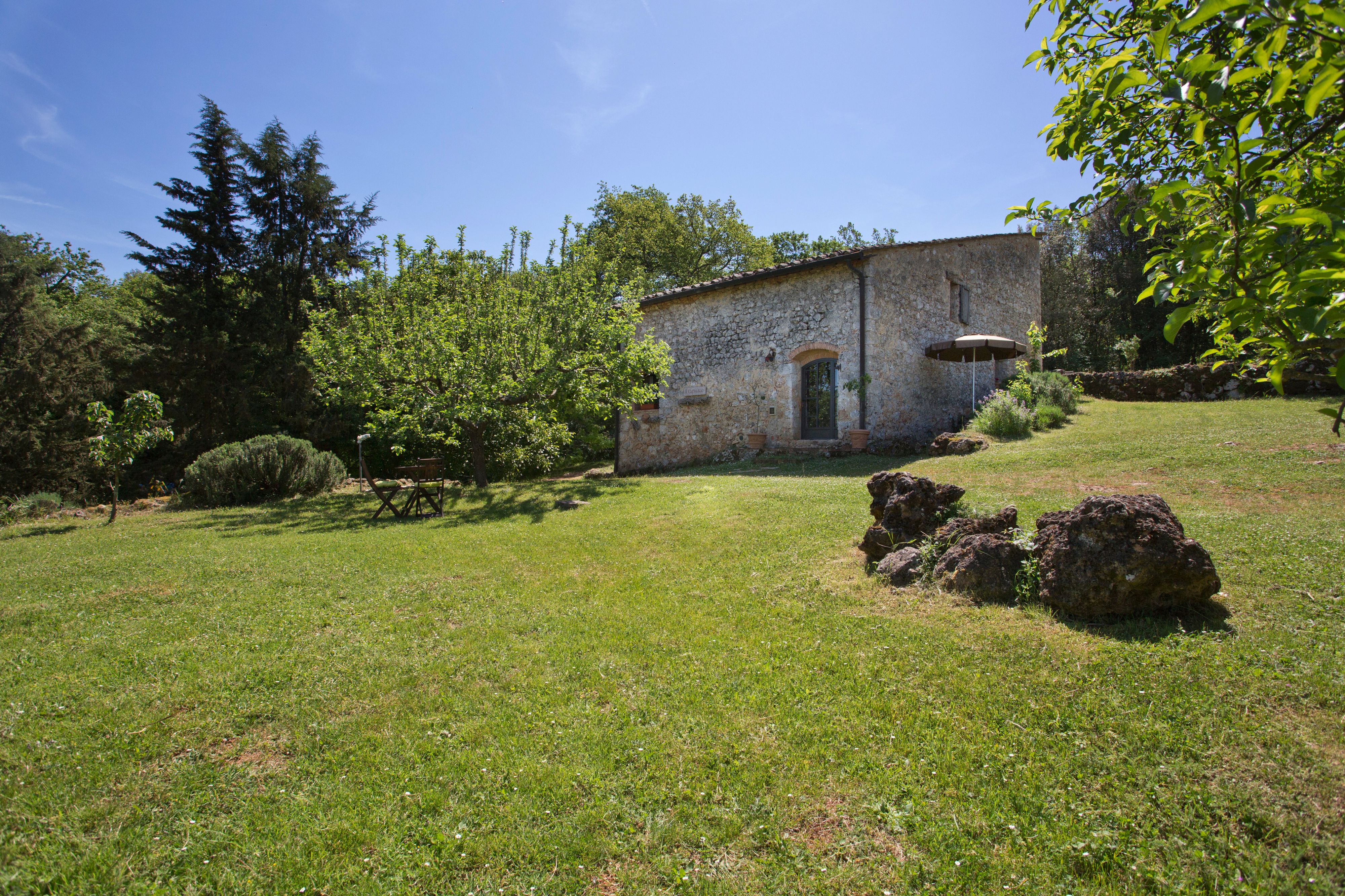 Edificio de piedra con puerta verde, rodeado de césped y árboles.