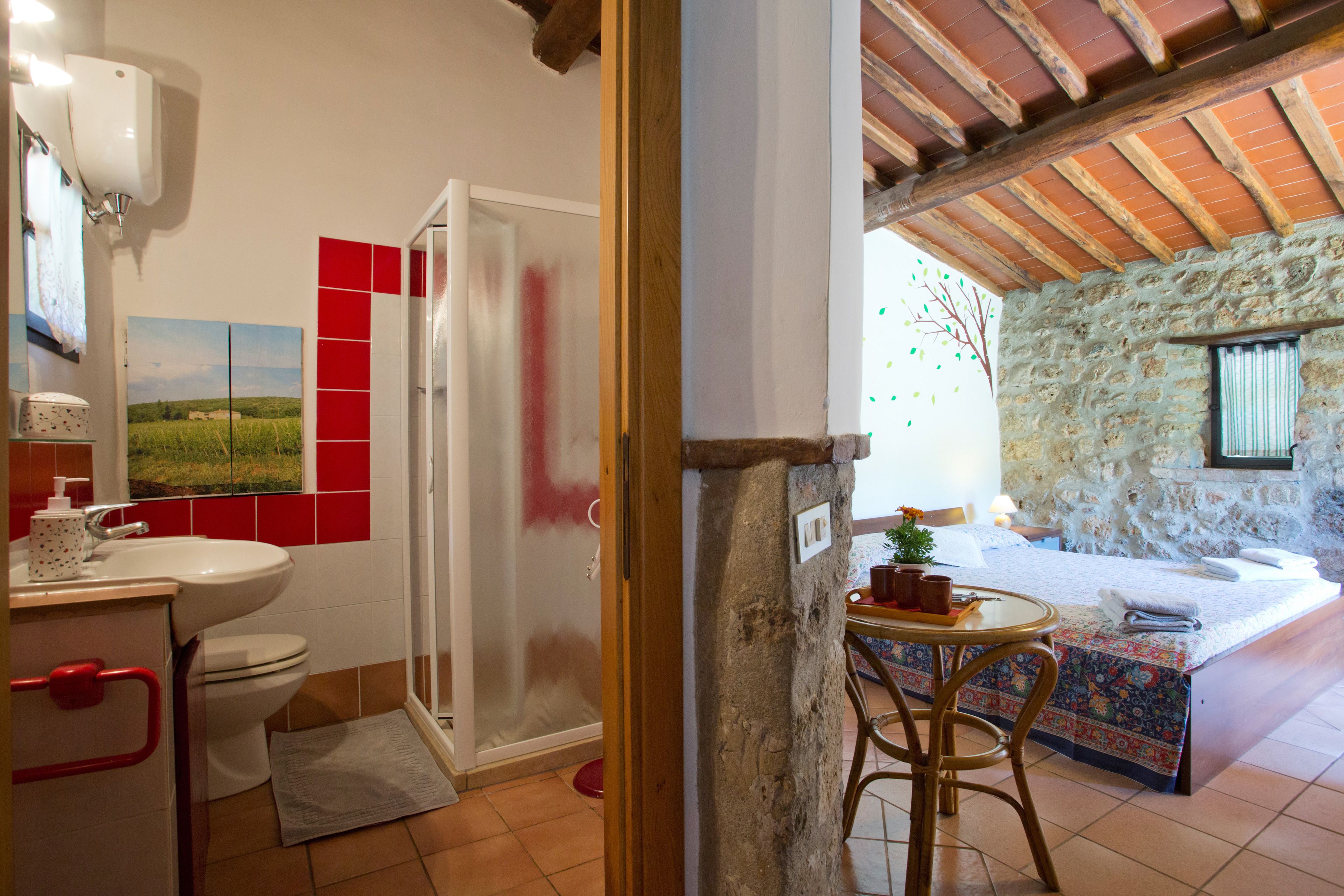 Un baño con inodoro, lavamanos y ducha. Hay una mesita con una silla y una ventana que ofrece vistas al exterior.