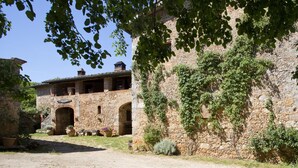 Ein rustikales Steinhaus mit Rundbogenöffnungen und einer überdachten Terrasse.