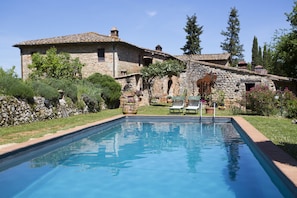 A stone house with a swimming pool, surrounded by greenery and a clear sky. - Agriturismo Novelleto (Monteriggioni)