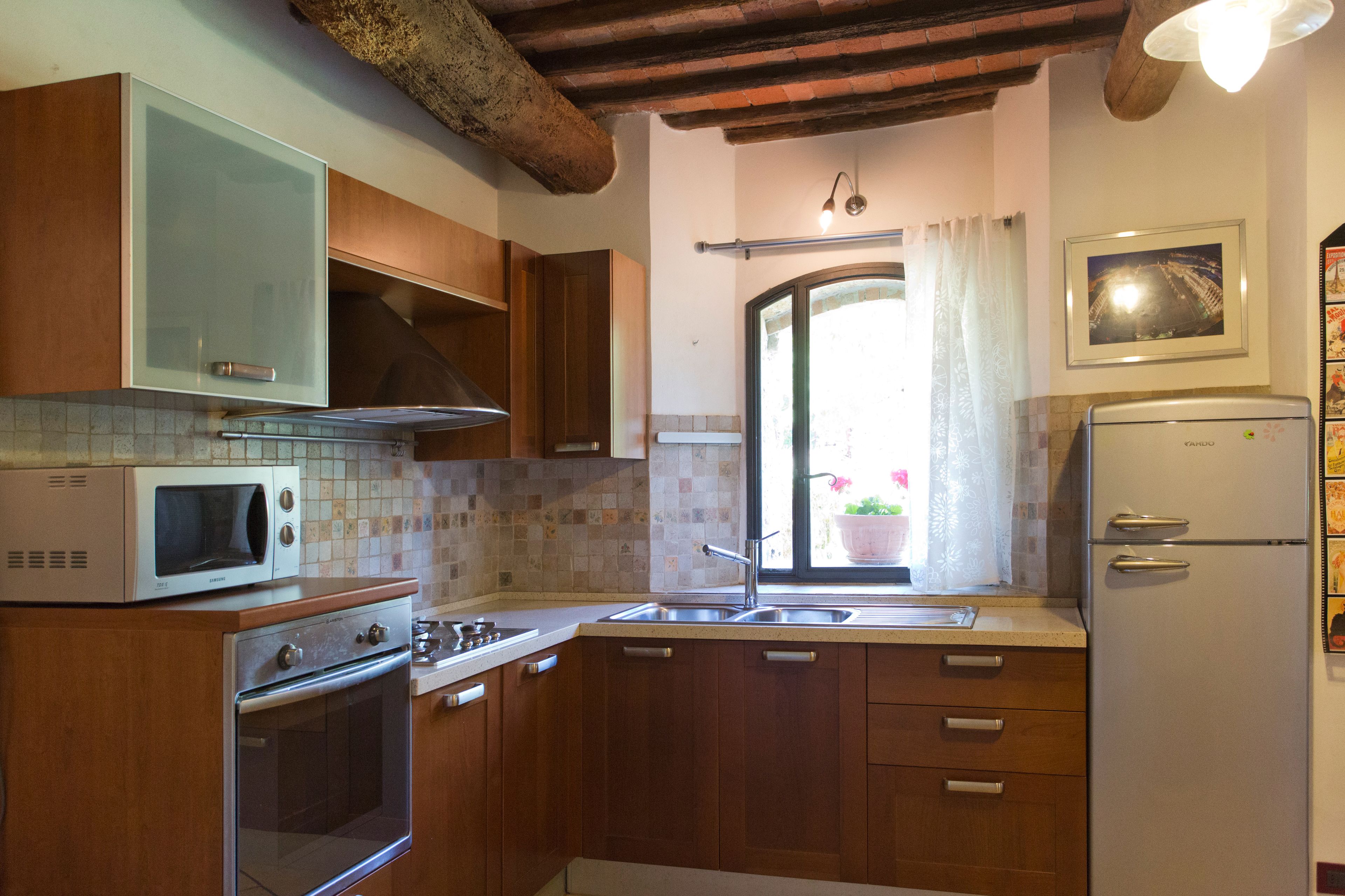 A kitchen with wooden cabinets, a microwave, a stove, a sink, and a refrigerator.