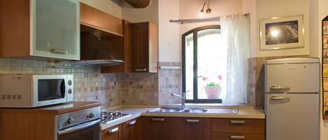 A kitchen with wooden cabinets, a microwave, a stove, a sink, and a refrigerator.