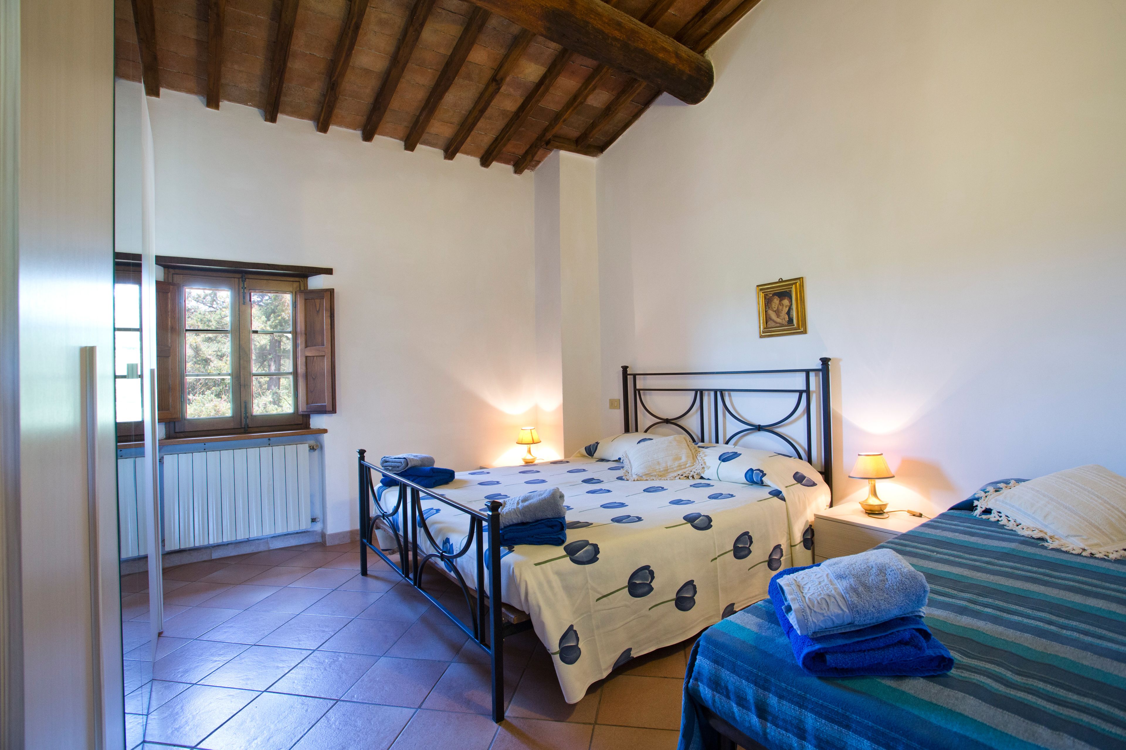 Una camera da letto con un letto, comodini, una finestra e un termosifone.