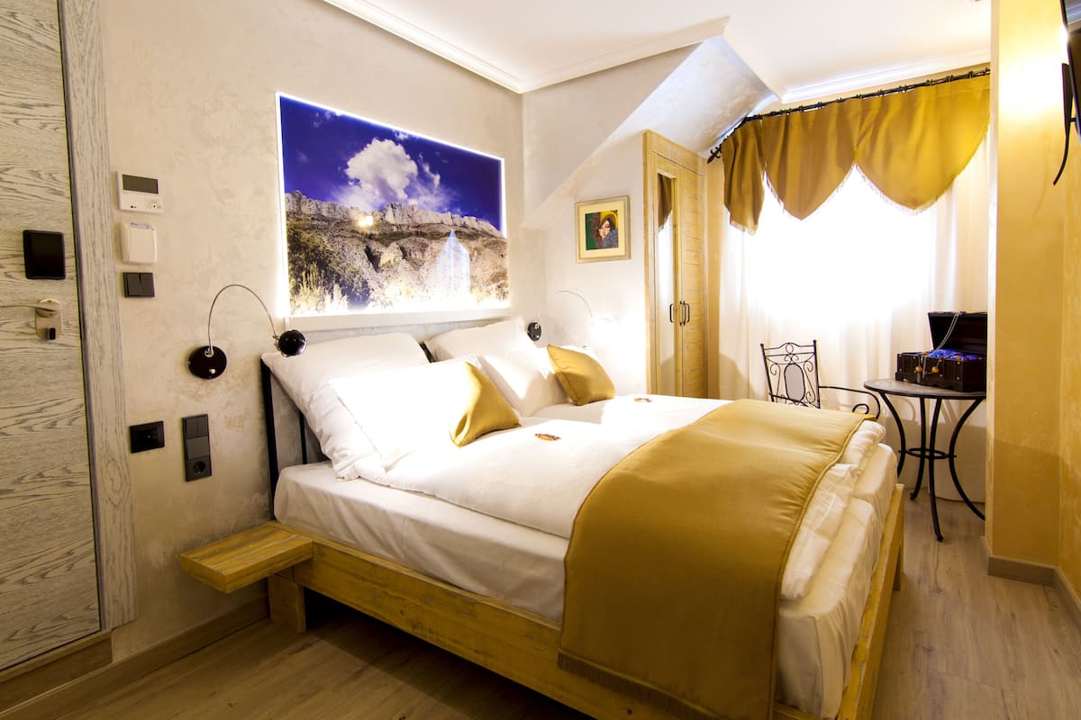 A bedroom with a bed, bedside table, and a painting on the wall.
