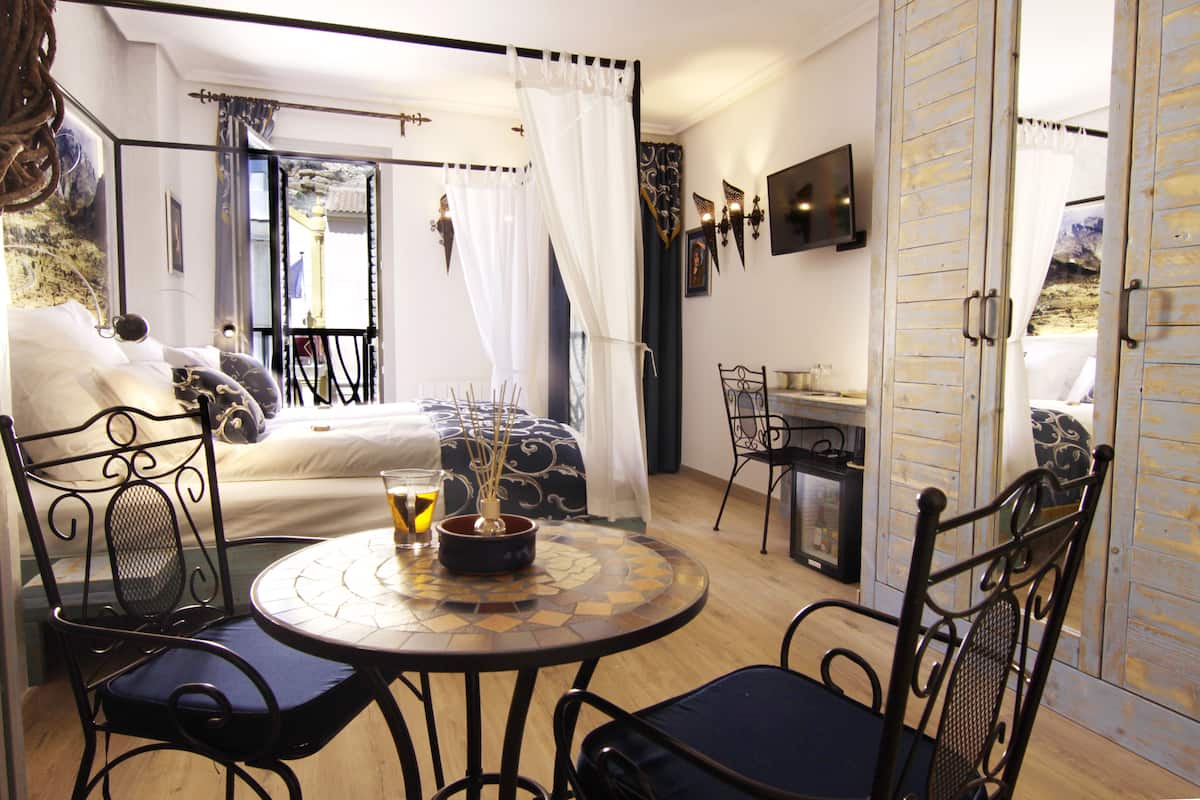 A bedroom with a bed, a small table with a vase, and a chair.